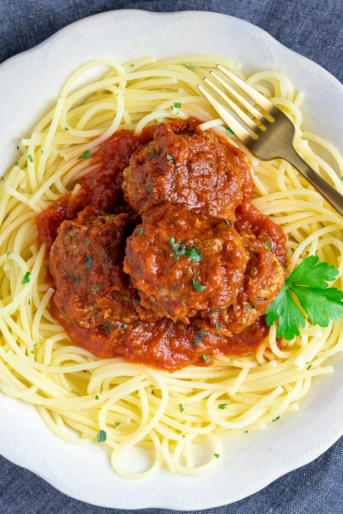 gluten and dairy free meatballs on top of spaghetti noodles in a white bowl with a fork